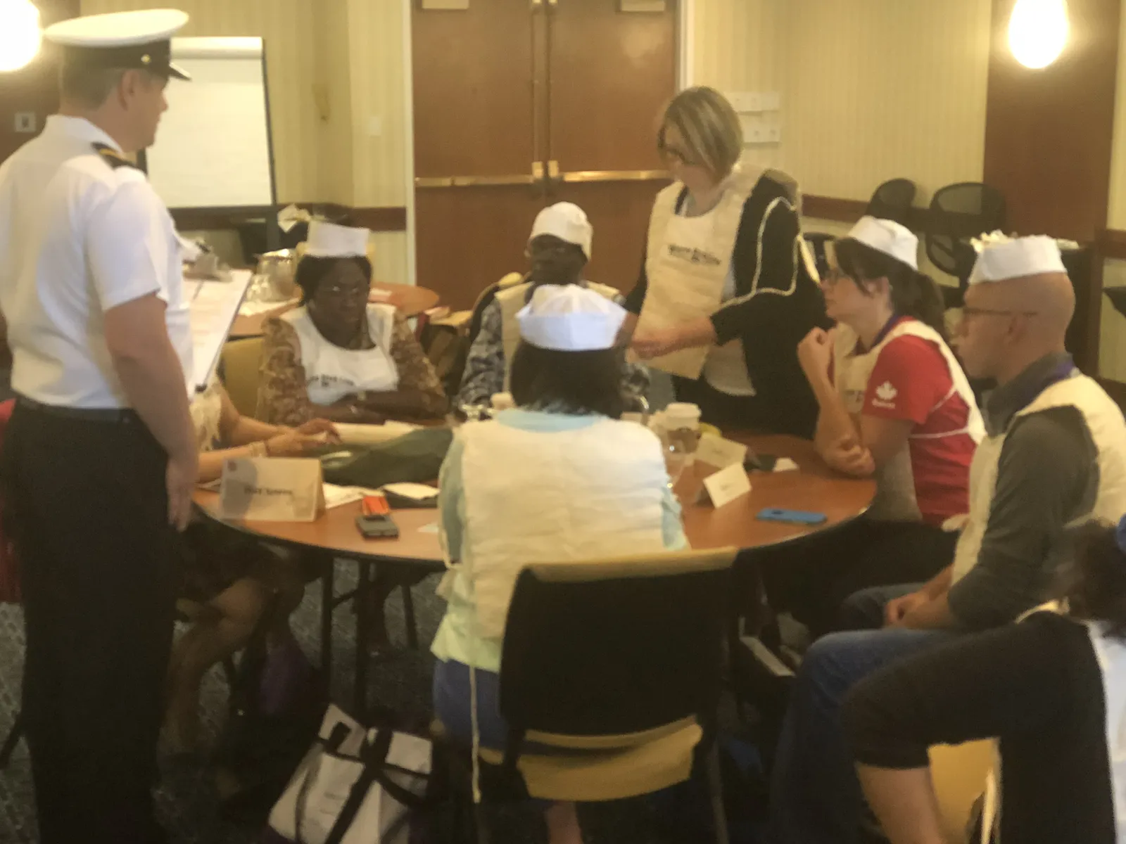 A facilitator engages with a diverse team seated around a cabaret-style round table during a Save the Titanic team development experience.